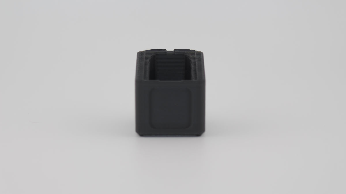 Back view of black Magpul PMAG 9mm +4 round magazine extension base plate displayed on light grey background