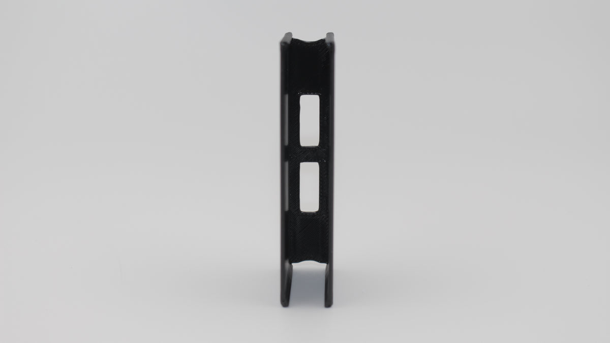 Front view of black 3D‑printed Carcano 6‑round en‑bloc clip showing central rectangular cutouts and symmetrical side walls on light gray background