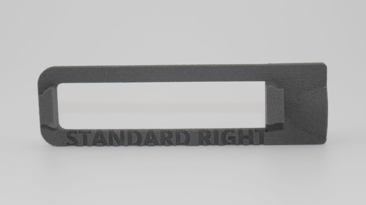 Back view of gray SLS 3D‑printed AUG brass deflector with rectangular open frame and raised mounting block, featuring embossed text 'STANDARD RIGHT', displayed on light gray background