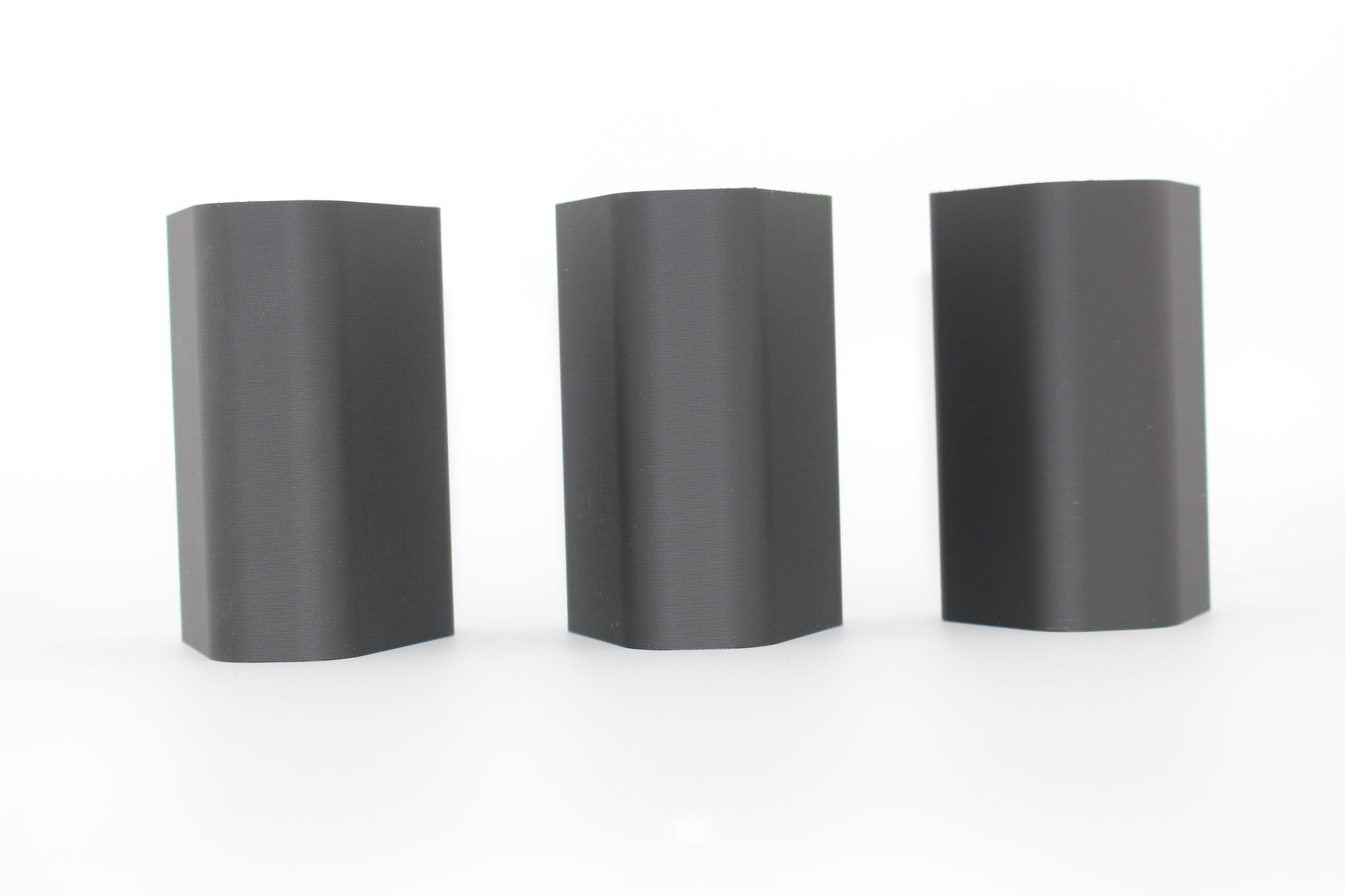 Top surfaces of three black half-size SBA3 cheek riser inserts representing 20mm, 17mm and 10mm heights, displayed upright with smooth, curved surfaces on a white background.