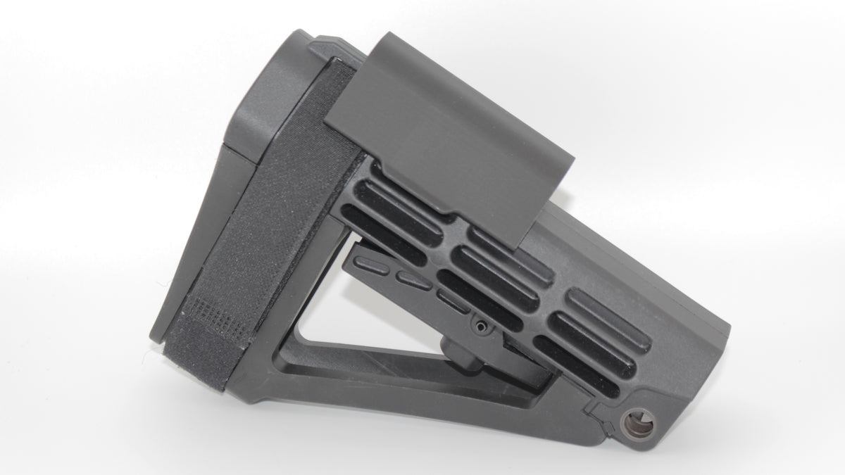 Side view of SBA4 modular cheek riser in the lowest mounting position attached to SBA4 brace, featuring black riser with smooth contoured top and skeletonized brace design, displayed on a light grey background.